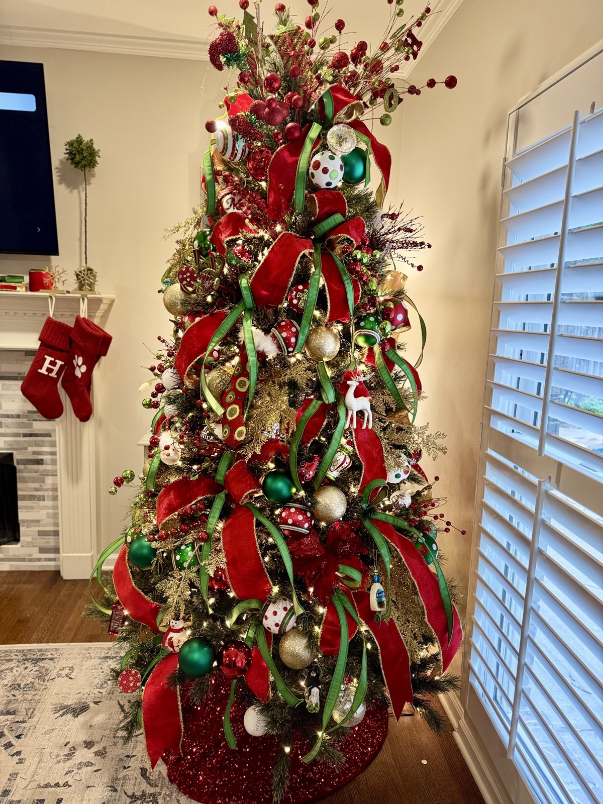 Traditional red, green and gold Christmas tree beside a stocking-hung mantel