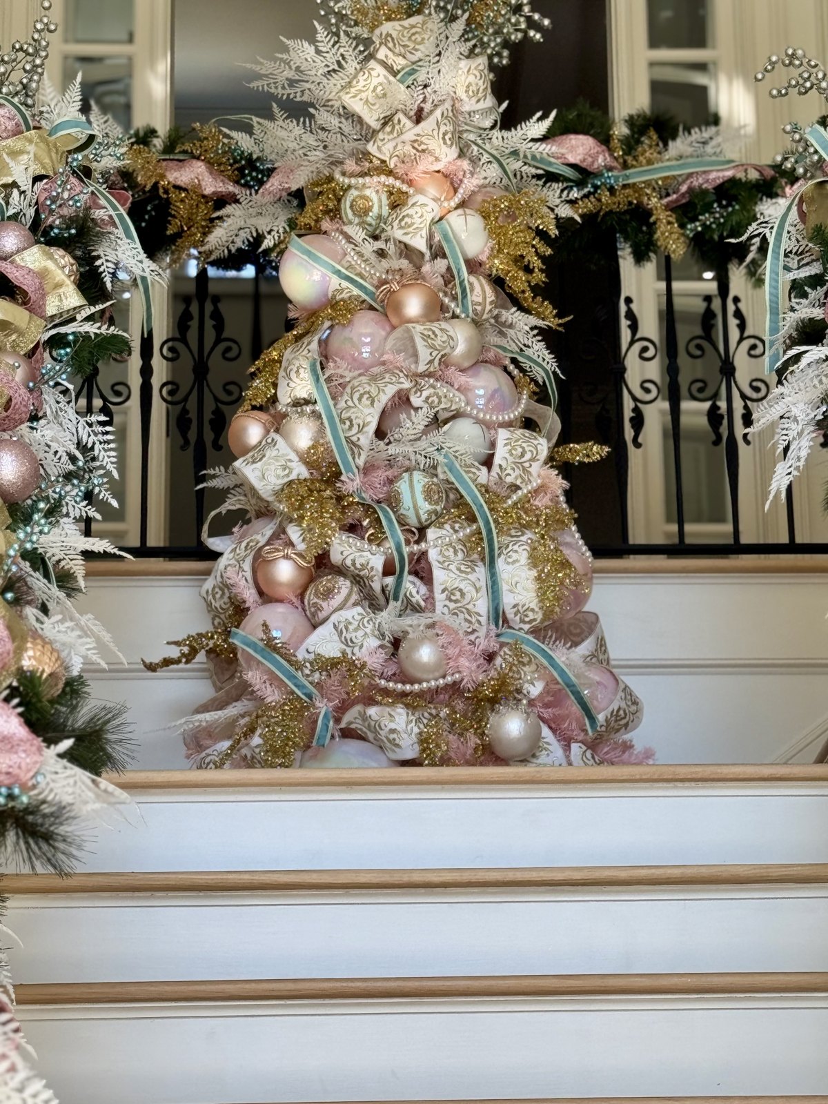 Staircase banister decorated with garland, gold ribbon and warm lights